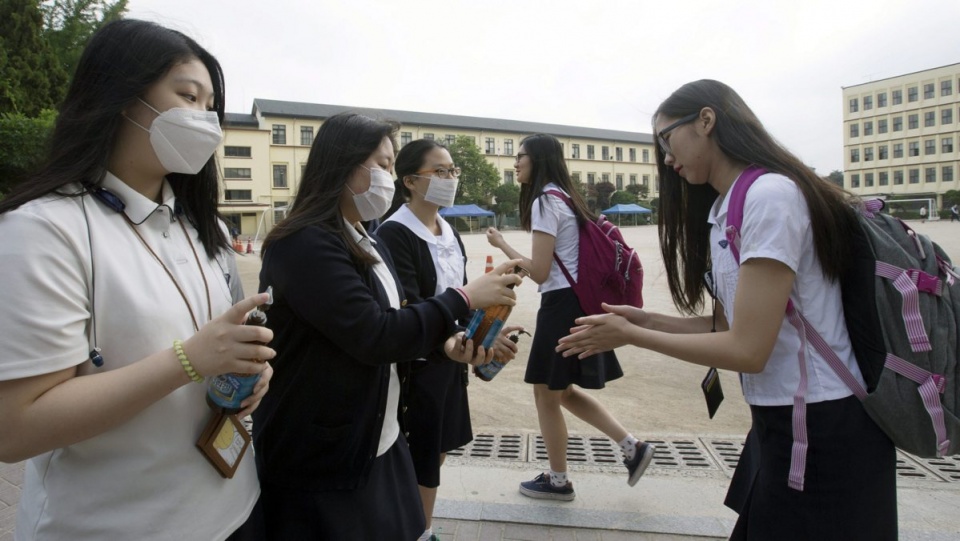 Studentki w Seulu dezynfekują dłonie przed wejściem do dali wykładowej. Fot. PAP/EPA