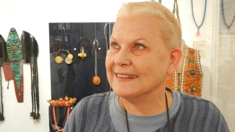 Elżbieta Dzikowska na tle wystawy "Ozdoba czy amulet" w Muzeum Podróżników. Fot. I. Muszytowska-Rzeszotek