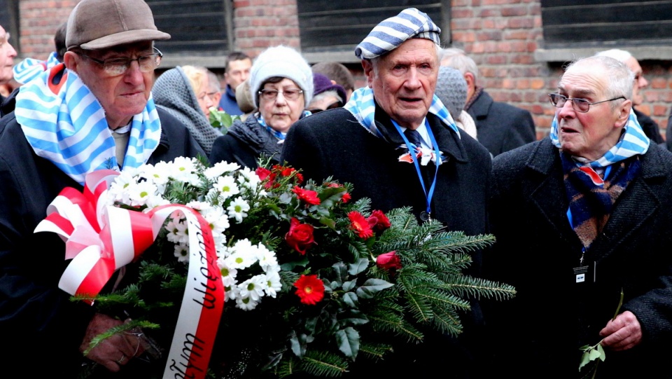 Byli więźniowie niemieckich obozów wieńca z biało-czerwonych róż i zapaleniem zniczy pod Ścianą Straceń w b. Auschwitz I. Fot. PAP/Andrzej Grygiel
