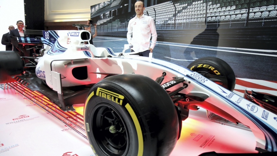 Na pierwszym planie zdjęcie bolid Williams, a w tle Robert Kubica, który w sezonie 2019 będzie znów kierowcą wyścigowym w Formule 1. Fot. PAP/Leszek Szymański
