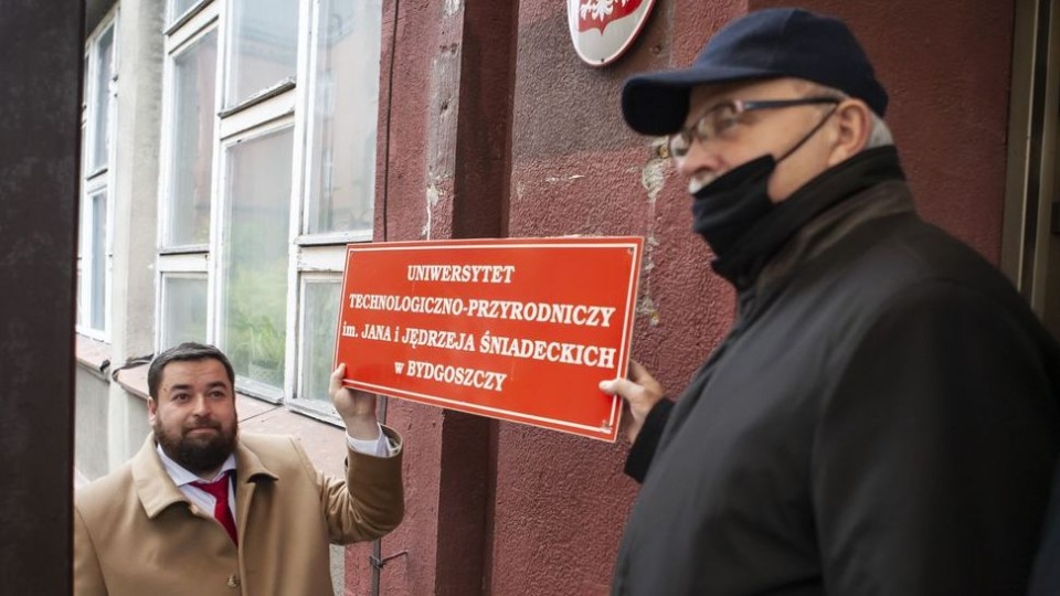 Rektor wraz z kanclerzem symbolicznie zdjęli z gmachu tablicę uniwersytetu/fot. materiały uczelni