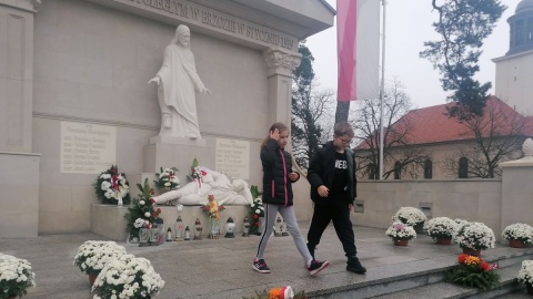 Uczniowie Szkoły Podstawowej im. Powstańców Wielkopolskich w Brzozie zapalili znicze dla poległych; w tle widać uszkodzoną figurę Chrystusa/fot. mg