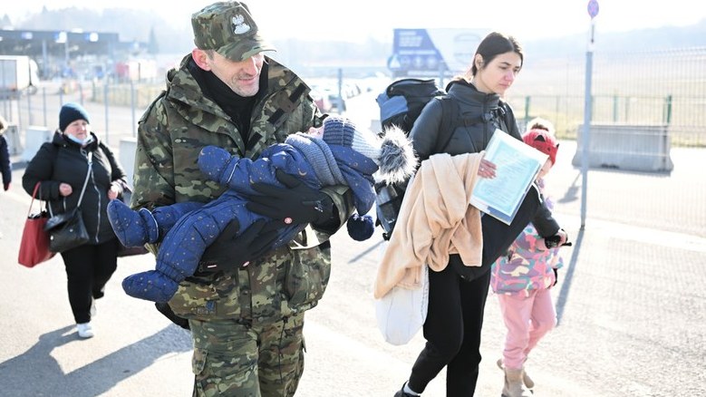 Przejście graniczne w Medyce. Strażnik graniczny pomaga kobiecie, która uciekła z dzieckiem z Ukrainy./fot. Darek Delmanowicz/PAP