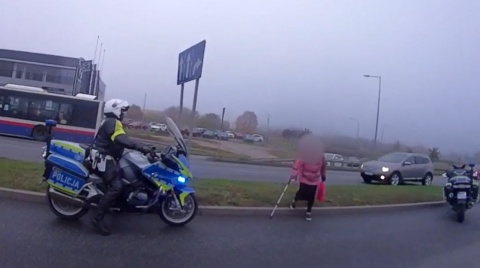 Starsza kobieta z kulą między pędzącymi autami. Policjanci wstrzymali ruch [wideo]