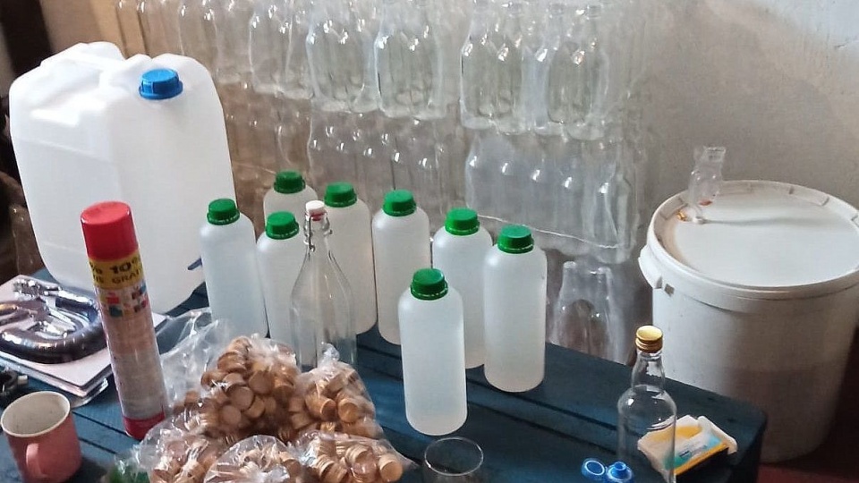 W trakcie przeszukania policjanci znaleźli 200 litrów wyrobów spirytusowych bez polskich znaków akcyzy, aparaturę do produkcji alkoholu, beczki, a także butelki, w które prawdopodobnie był rozlewany. Fot. Policja
