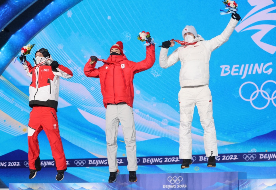 Austriak Manuel Fettner, Japończyk Ryoyu Kobayashii Dawid Kubacki w skoku radości podczas ceremonii dekoracji medalistów w skokach narciarskich na obiekcie normalnym.