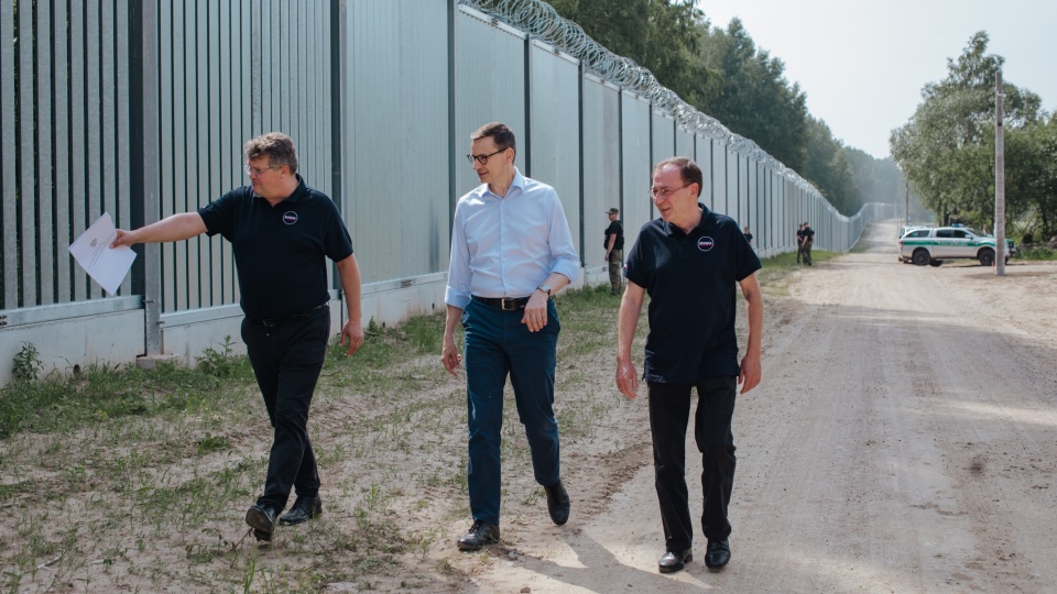 Mariusz Kamiński, pierwszy z prawej i Maciej Wąsik, pierwszy z lewej, razem z byłym premierem kontrolują zaporę na granicy z Białorusią/fot. By Gov.pl, CC BY 3.0 pl, https://commons.wikimedia.org/w/index.php?curid=126816045