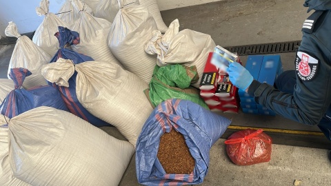 Na terenie posesji oraz w garażu należącym do kierowcy, funkcjonariusze KAS znaleźli 18 worków zawierających ponad 156 kg tytoniu do palenia, a także 2580 sztuk papierosów nieposiadających znaków akcyzy/fot. KAS